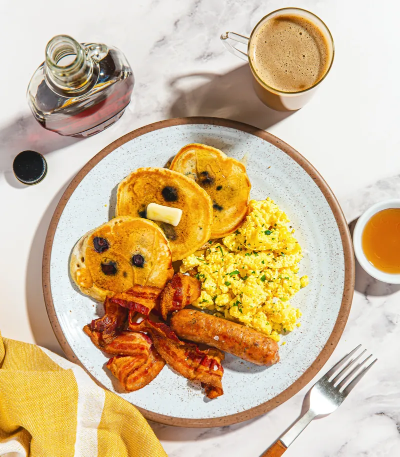 Blueberry Pancakes with Eggs, Pork Sausage, Bacon "Grand Slam", a Forkful-style prepared meal